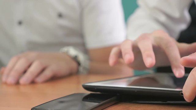 Close-up of hand of man dressed in white shirt sits at desk at office the resting and looking at favorite photos using the screen of computer tablet in white-black colour.
