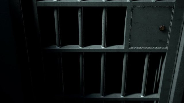 A static camera closeup of a heavy welded iron jail cell door slamming shut on a dark moody background