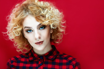 Portrait of a beautiful young girl with curly hair on a red background