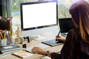 Young hipster graphic designer woman using digital graphic tablet while working at modern office, professional female retoucher sitting at modern workspace with wooden table