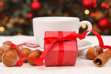 Wrapped gift, cup of tea or coffee and christmas tree with lights
