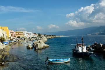 Fototapeta na wymiar Coastline with rocks and a fisherman's in foreground under blue