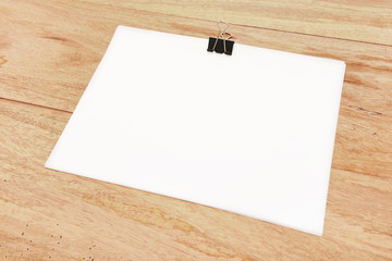 Blank paper with paper clip on wood board