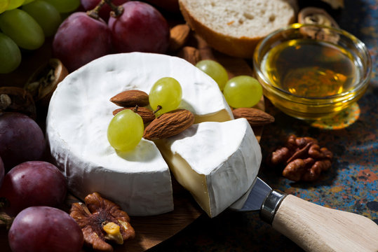 Camembert cheese, fruits and honey on a dark background