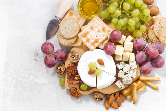 camembert, grapes and snacks on a white table, top view