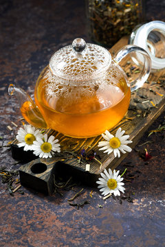 chamomile tea in a glass teapot and dark background, vertical top view
