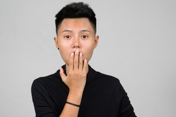 Portrait of Asian young tomboy covering mouth with hand