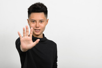 Portrait of Asian girl with tomboy style smiling and showing stop sign with hand