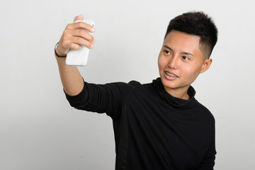 Young happy person using phone to take selfie while smiling