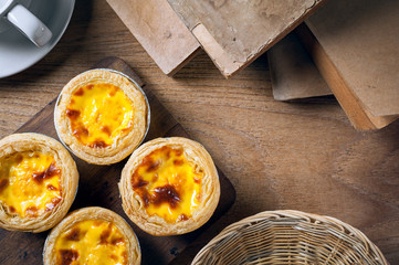 Delicious Egg tart, traditional Portuguese dessert, on wooden plate for coffee break on rustic wooden table.