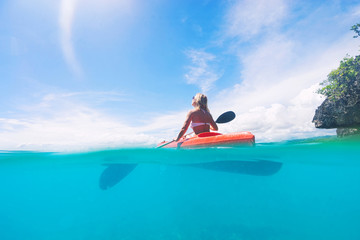 Lady paddling the kayak in the calm tropical bay with blue sky on background. Split photo. Selective focus.