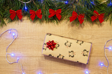 New Year / Christmas gift in package, tree with red bows and blue garland on the wooden background template