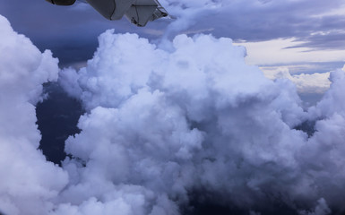 Evening blue sky. Flying above clouds. Looking through an airplane window.