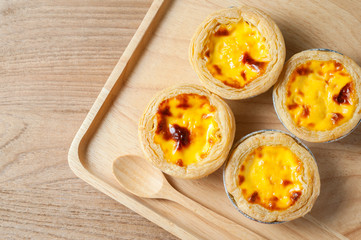 Delicious Egg tart, traditional Portuguese dessert, on wooden plate for coffee break on rustic wooden table.