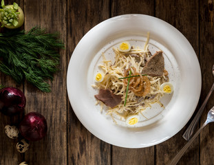 a dish of meat and cheese, decorated with quail eggs and onion on wooden boards, top view
