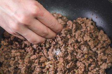 Add salt and pepper to minced meat in a frying pan, close up