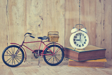 Bike with stop watch at 9am and old book on wooden floor. Vintage ideas