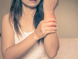 Health care concept. Woman massaging her painful arms, red hi-lighted on pain area.