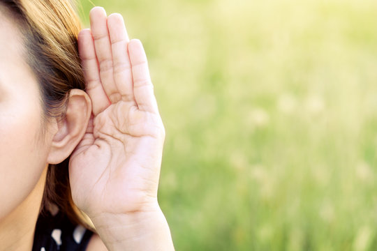 Asian Woman Hold Her Hand Near Her Ear And Listening In Green Field