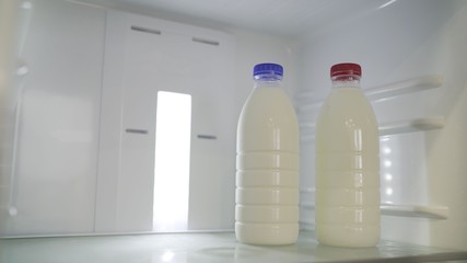 a bottle of milk in the fridge. Two bottles of milk in the refrigerator. A bottle of milk with a blue lid. Bottle with milk with a red cap