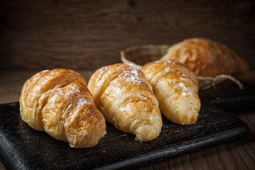 Fresh baked croissant sprinkled with powdered sugar on table