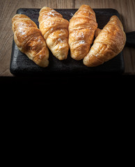 Fresh baked croissant sprinkled with powdered sugar on table