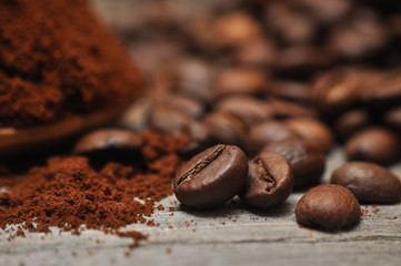 Milled coffee and coffee beans on old wooden background
