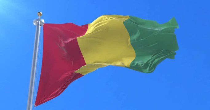 Flag of Guinea waving at wind in slow in blue sky, loop