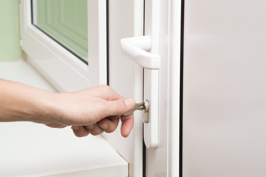 Woman's hand opening the white plastic door with key.