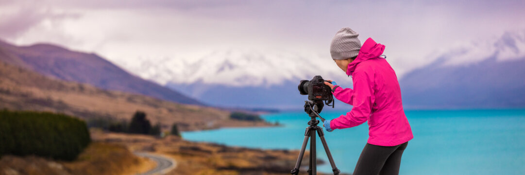 Woman photographer taking picture of travel landscape panoramic banner. New Zealand nature photography with slr camera on tripod at sunset with autumn background at Peter's lookout