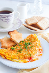 Breakfast with an omelette with tomatoes and cheese, tea and biscuits, selective focus