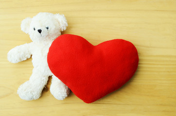 Valentines Day. Teddy Bear Loving cute with red heart pillow on wooden backgrounds above. Place for your text