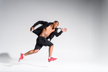 young african american sportsman running on grey