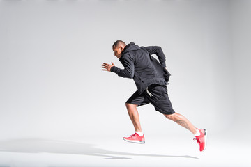 side view of young african american sportsman running on grey