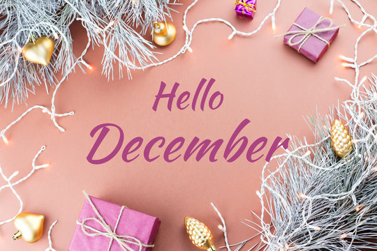 Hello December greeting card with fir tree, purple giftboxes, golden ornaments and Christmas lights in brown background
