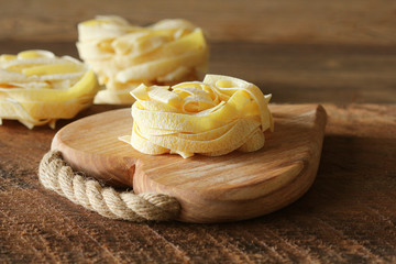 Raw italian pasta tagliatelle on wooden cutting board
