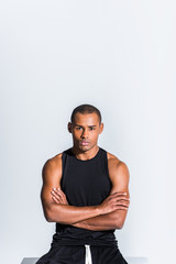 confident young african american sportsman with crossed arms looking at camera isolated on grey