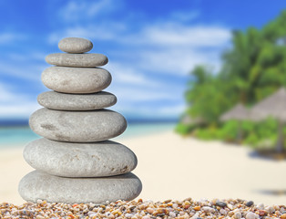 Fototapeta na wymiar Small zen stone with beautiful sand and palm tree beach background for spa and balance symbol