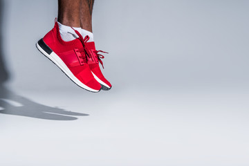 cropped shot of young african american sportsman in sneakers jumping on grey