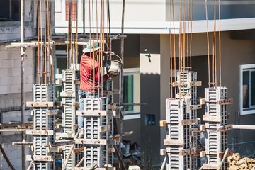 Worker pouring concrete to formwork at construction site to building house
