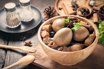 Eggs and pork boiled in the gravy on wooden table, Thai food.