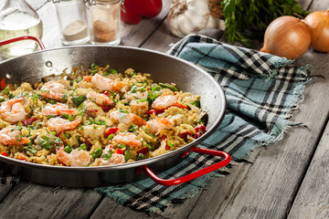 Traditional seafood paella with shrimp, fish and chicken seved in paellera