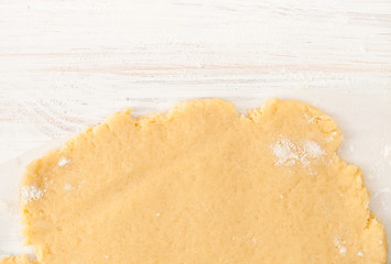 The rolled out shortcrust pastry on a white table. View with copy space