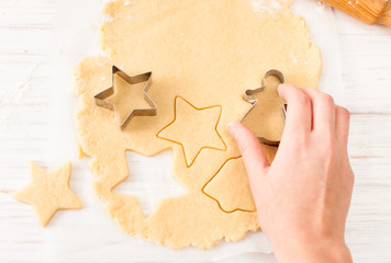 Cut the cookie shape from the dough at the white table. View with copy space