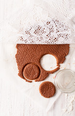 Cut biscuit shapes out of the chocolate dough on white table. View with copy space
