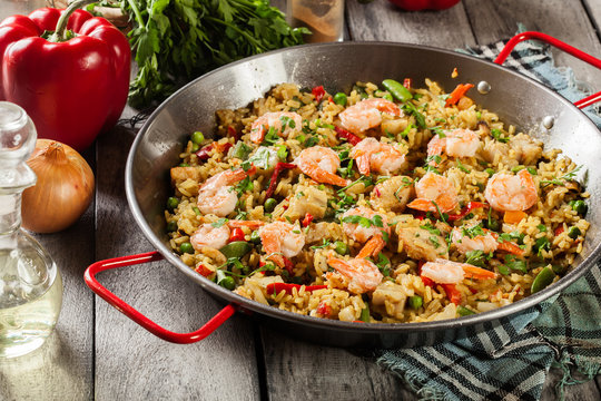 Traditional seafood paella with shrimp, fish and chicken seved in paellera