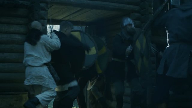 Large-Scale Medieval Battle Reenactment. Violent Tribe of Warriors Run Through The Gates of the Wooden Fortification and Attack Guards. Shot on RED EPIC-W 8K Helium Cinema Camera.