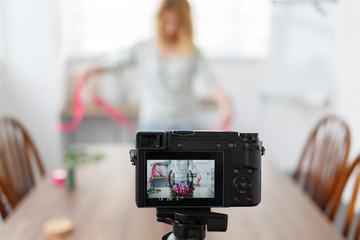 Defocused photo of a blogger's florist recording to the camera a master class for making a bouquet of pink flowers. Focus on the camera