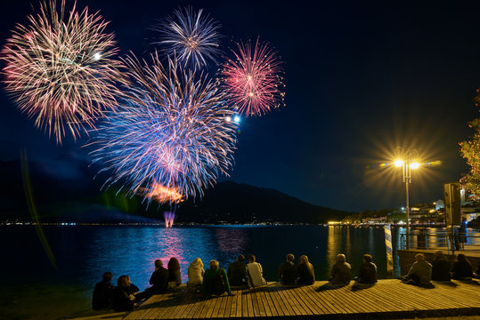 Crowd watching fireworks and celebrating. Beautiful firework display for celebration on the Garda Lake,italy,Brightly Colorful Fireworks