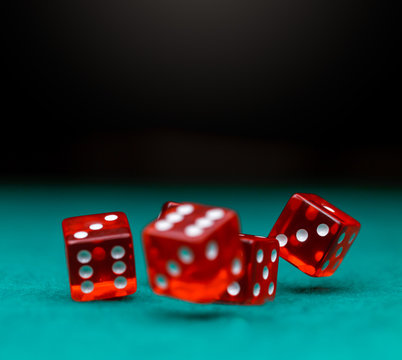 Image of several red dice falling on green table
